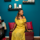 Wendi Cherry sitting in a room with blue walls wearing a yellow dress.
